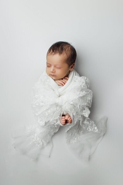Newborn baby sleeping and wrapped in white lace, taken by nj newborn photographer Ally Kimpton Photography