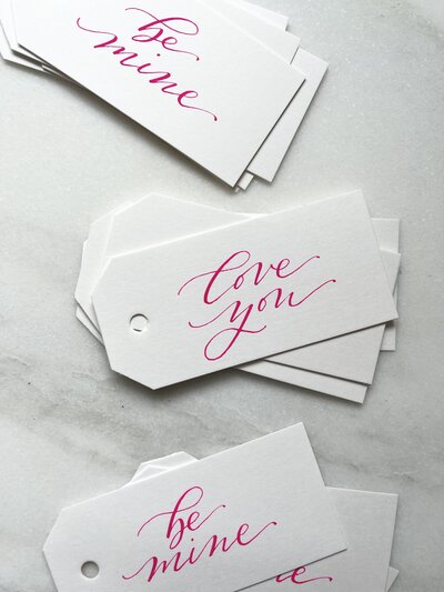 White gift tags with bright pink calligraphy for Valentine's Day