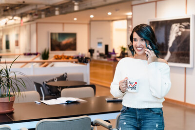 business coach picking her phone and holding a brand  coffee mug.