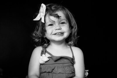 Luxury Family Portraits by Moving Mountains Photography in NC - Black and white photo of a little girl smiling at the camera.