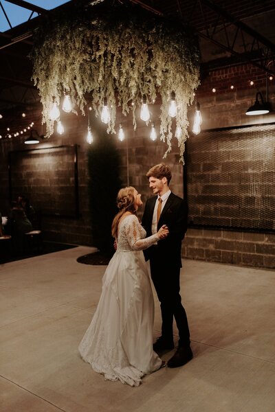 bride and groom dancing under lights
