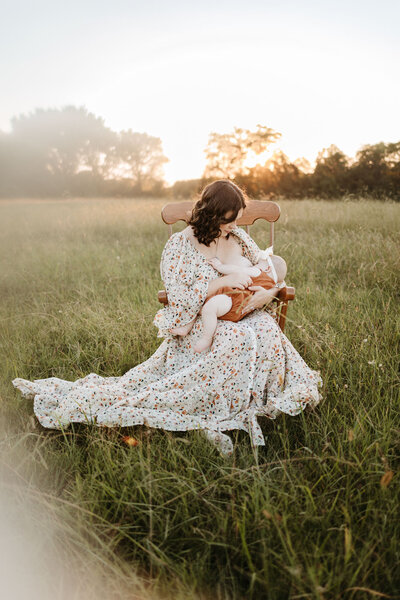 mom holding baby in field and sitting on chair