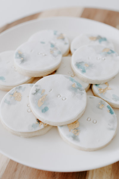 Sugar cookies topped with fondant, blue edible paint, gold leaf, and stamped "I DO" in block letters