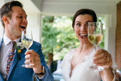 a bride and groom cheers their wine and laugh over some silly faces