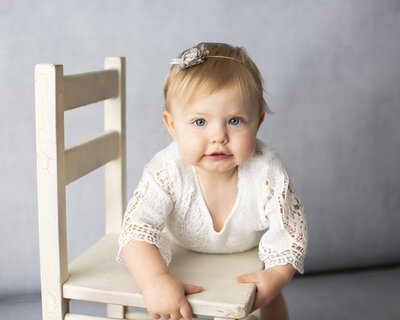 baby girl smiling at camera on a chair