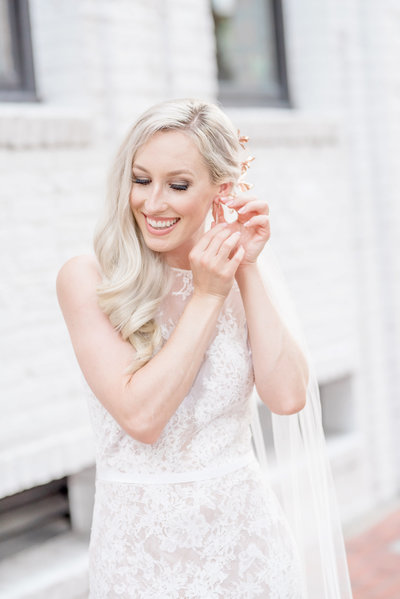 Beautiful bride adjusts her jewelry on her wedding day