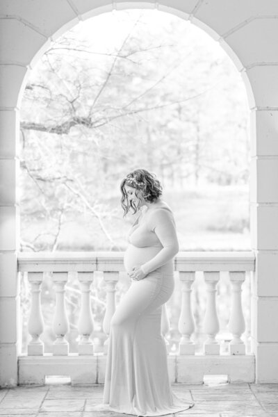 mom looking at belly under an arch during Warrenton, VA maternity photos