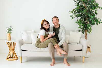 Married photography duo Sarah & Ben sit on a couch drinking coffee