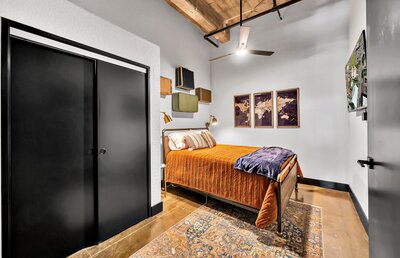Bedroom with flat screen TV in this two-bedroom, two-bathroom vacation rental condo in the historic Behrens building in downtown Waco, TX just blocks from the Silos, Baylor University, and Spice Street.