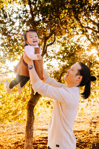 Family Photographer, dad is holding daughter in air
