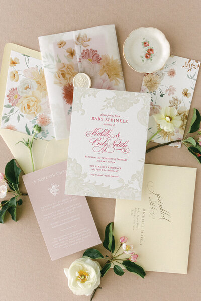 Chic letterpress baby shower invitation in shades of pink and yellow, featuring a floral envelope liner, vellum jacket, and yellow oval wax seal.