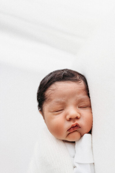 Gorgeous newborn baby sleeping on a white beanbag on their newborn photoshoot in Cheshire