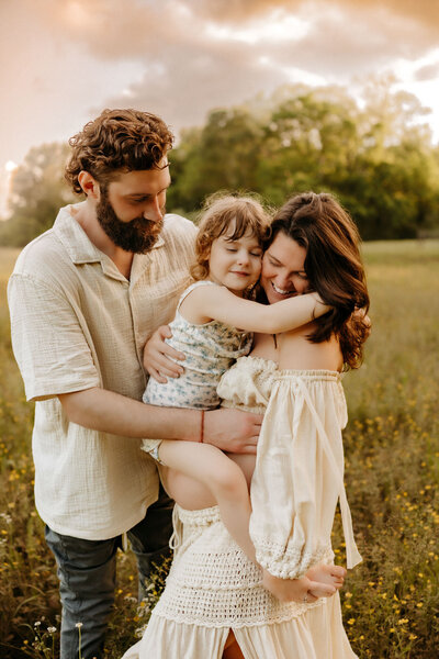 family hugging in a field at golden hour