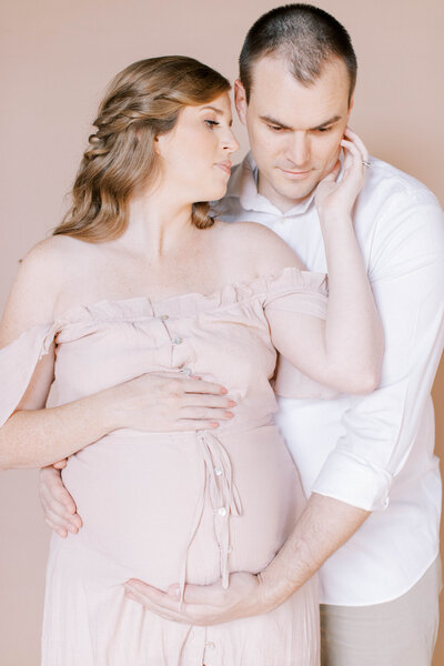Sweet editorial maternity session mom and dad snuggle close at studio in Kansas City