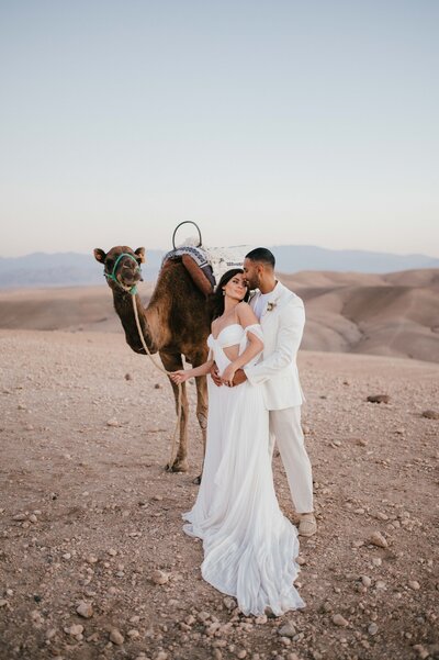 Megan and James with a camel after their wedding at Be Agafay Morocco.