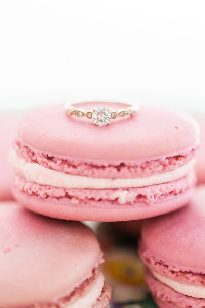 Close-up photo of an engagement ring on a pink macaroon for an engagement portrait by Jennifer Marie Studios in Atlanta Georgia.