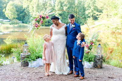 bride and groom smiling at a flower girl and ring bearer