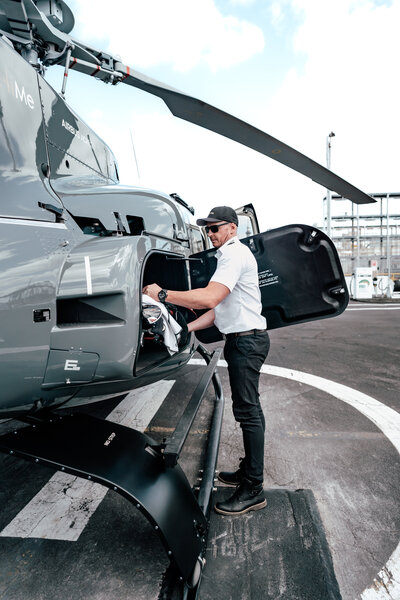 A pilot loading golf bags into the back of a Luxury Airbus Helicopter during the Commercial Photography Session captured by Zanthe Vorsatz Photography