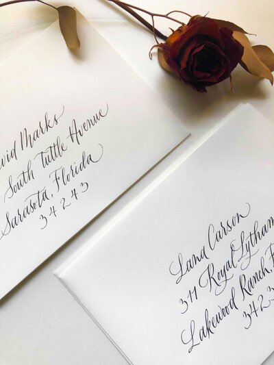 stack of calligraphy envelopes with dried rose to the side