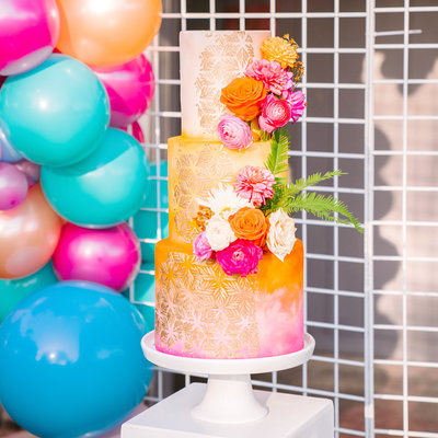 boho wedding cake with flowers and balloon arch