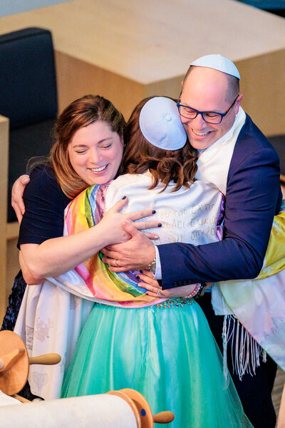 A mother and father hug their daughter during her bat mitzvah
