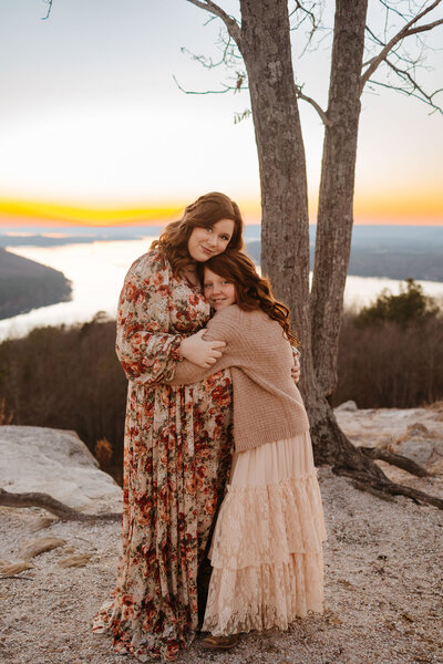 mom and daughter hugging on cliffside