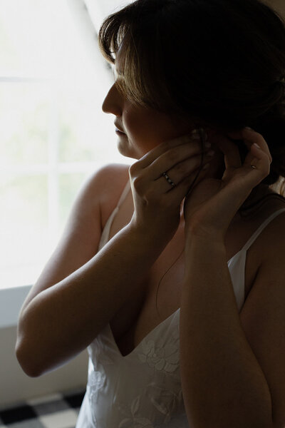 bride getting ready and putting on an earring