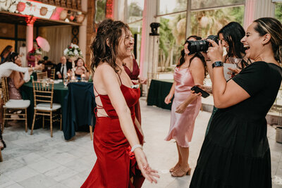 photographer taking a picture of a woman in a red dress while they both smile