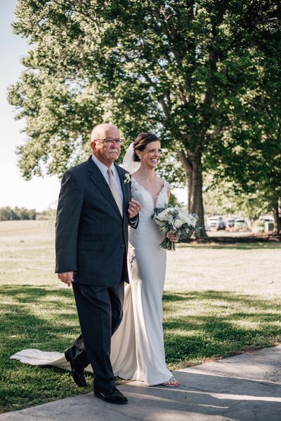 bride and father walking down the aisle together during her outdoor wedding ceremony in Hampton Roads wedding venue