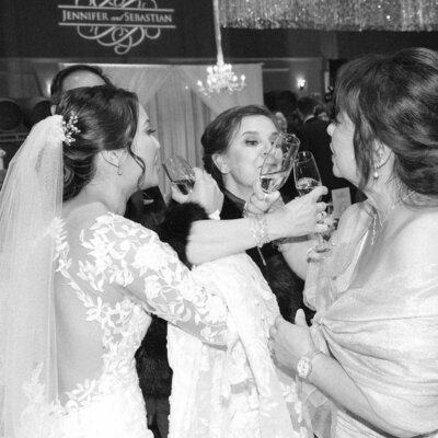 Bride links arms with three other people as she drinks champagne to celebrate just getting married