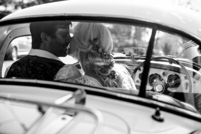 bride and groom kissing in vintage car black and white photo