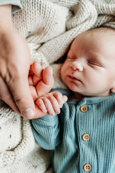 Baby holding dad's hand for newborn photography at home
