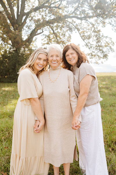 mom, daughter, and grandmother standing together under tree