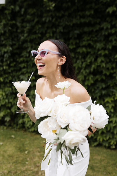 Happy bride holding a cocktail  and laughing