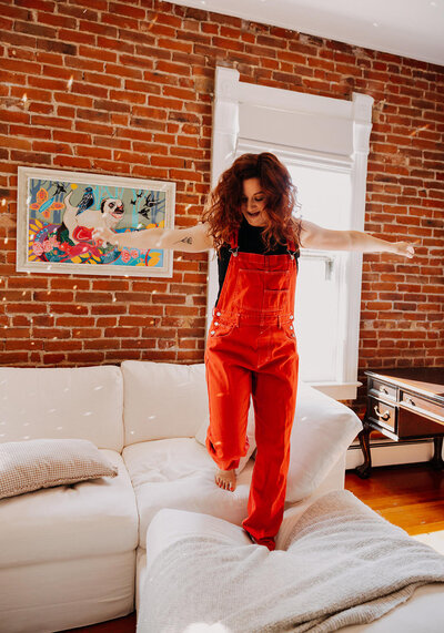 A woman jumping on a couch.