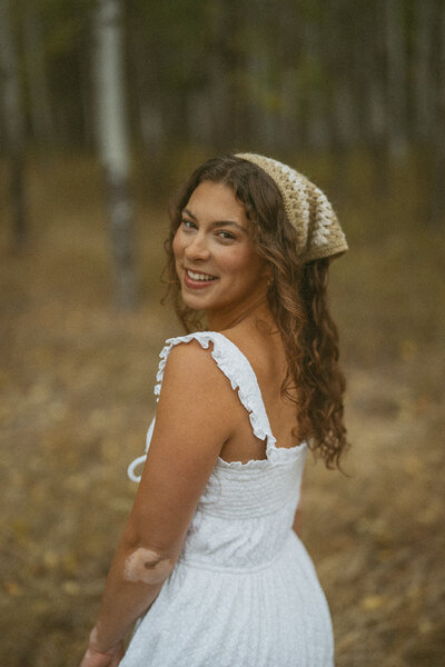 Emily Noelle, Portland senior photographer, smiling in a bandana and white dress