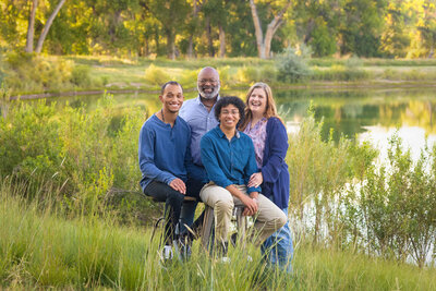 family of four standing in a green field near a pond