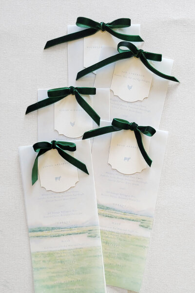 Gorgeous wedding menus for a summer wedding in Jackson, WY,  featuring a delicate vellum overlay print with a watercolor illustration of the venue. Each menu is personalized with a place card tied with a luxurious velvet ribbon, adding a soft, sophisticated touch.