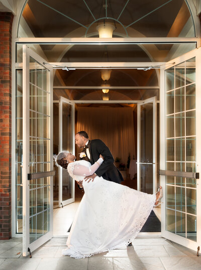 A groom dipping a bride in a grand doorway.
