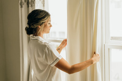 bride holds curtains