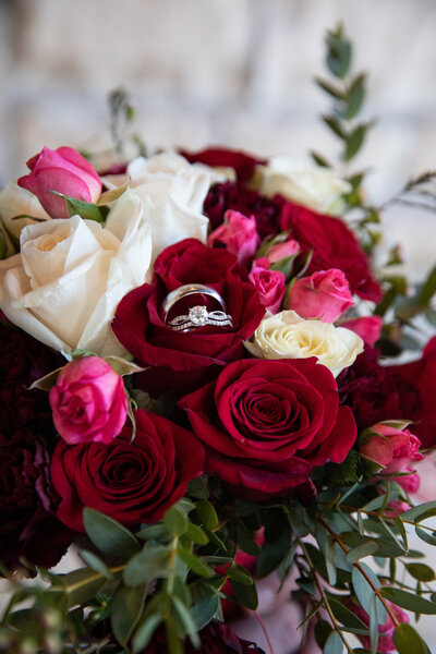 A stunning bouquet of red and white roses, beautifully accentuated by an elegant wedding ring.