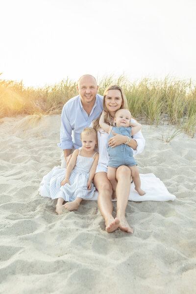happy family of four smiling for family portrait photos at Greenwich Beach in Connecticut