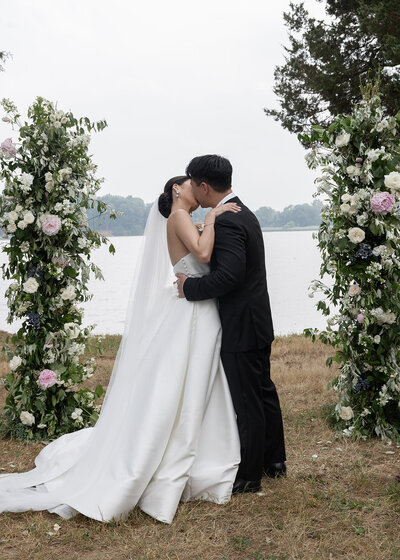 Newly married couple kissing under flowers