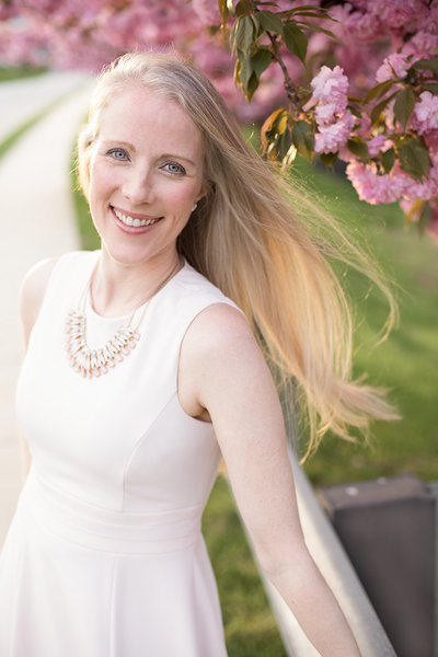 Outdoor headshot of Maryland Newborn Photographer Rebecca Leigh in front of cherry blossom trees