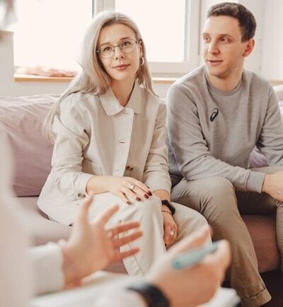 A couple sit next to one another while a person gestures with their hands. This could symbolize what a couples therapist might do during couples communication therapy in Florida. We offer communication therapy for couples in Florida and other services. Contact a communication therapist in Florida today!