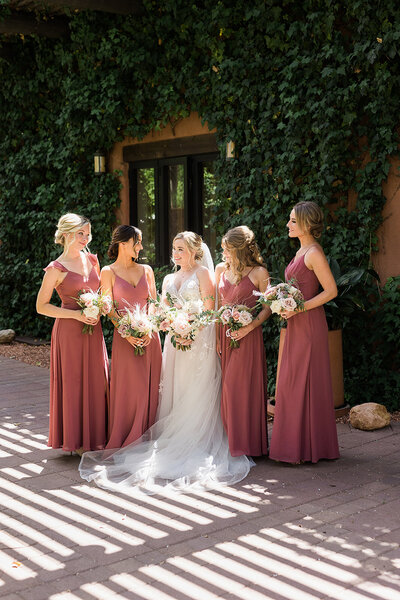 Bride and bridesmaids wearing dusty rose dresses and holding bouquets