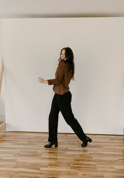 woman walking away looking back and smiling in a studio