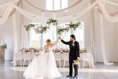 bride twirling holding grooms hand in reception space
