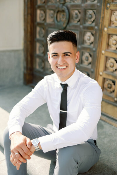 Photo taken by Monette Wagner Photography of high school senior boy sitting down smiling on Indiana World War Memorial stairs in front of gold door