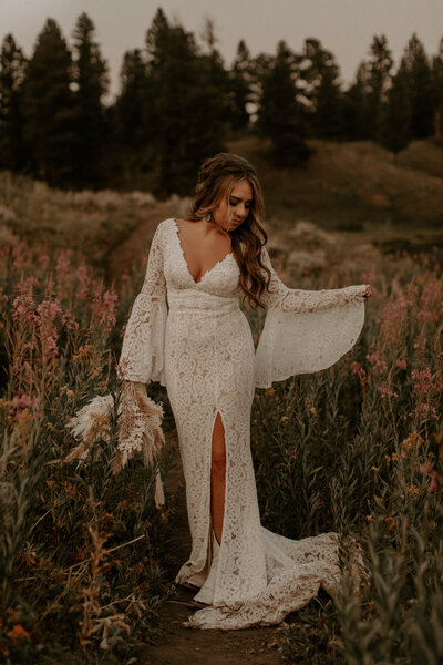 Boho bride with loose curls and a lace dress in a flower field
